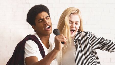 Karaoke party concept. Happy diverse friends singing together at homeの写真素材