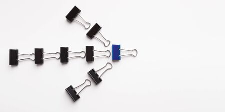Direction concept. Arrow sign made with black paper clips, white panorama background with empty...