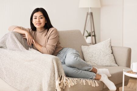 Relaxed Asian Girl Enjoying Rest on Comfortable Sofa, Free Spaceの写真素材