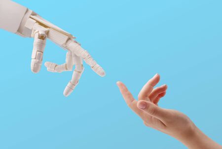 Connection between people and artificial intelligence technology. Female hand and robot reaching to...