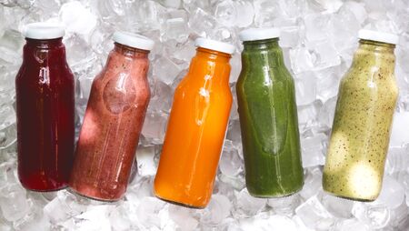 Healthy breakfast. Five day ration of different fresh detox drinks in glass bottle on ice background, panoramaの写真素材