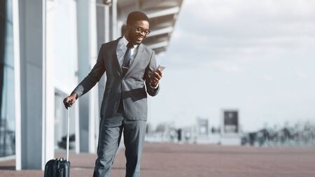 Check E-mail. Afro Businessman Arriving at Airport and Using Phone Outdoors, Copy Spaceの写真素材