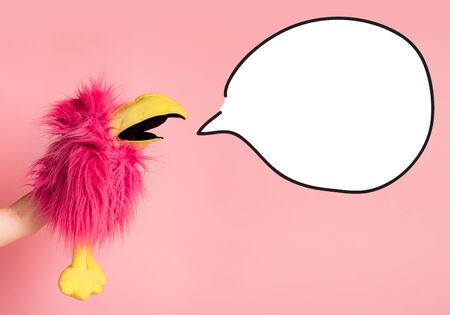 Summer sales concept. Toy Pink bird in hand cry to white bubble for advertisement text, blank spaceの写真素材