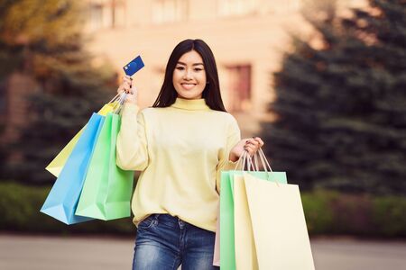 It makes shopping easier. Girl holding shopping bags and credit card, walking outdoors