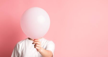 Promotion advertisement. Woman hiding her face beside pink balloon with blank space for text, panorama, copy spaceの写真素材