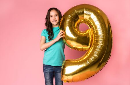 Cute girl with number 9 balloon over pink studio background
