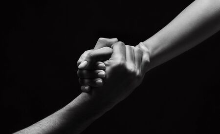 Strong connection. Unrecognizable woman hand helping man to stand up on background, black and white