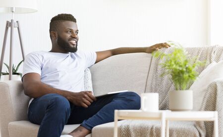 Comfortable weekend. Peaceful african man resting at home, planning activities, empty spaceの写真素材