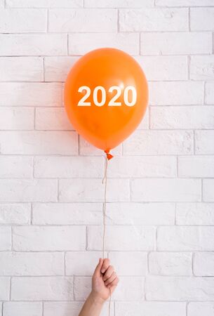Halloween 2020. Orange balloon with white text in hand on bricks wall, vertical panoramaの写真素材