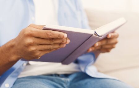 Reading is interesting. African-american man holding book in hands, closeup