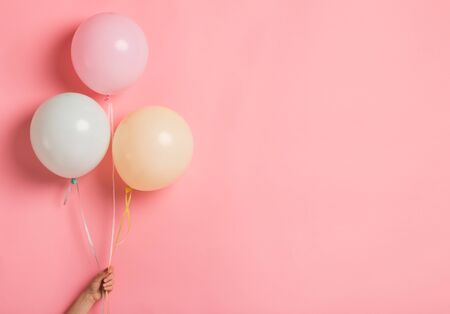 Happy birthday. Party balloon bunch in woman hand on pink background, copy spaceの写真素材