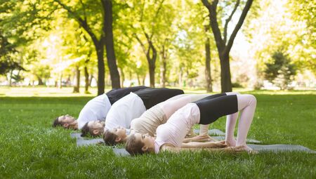 Flexible Young People Practicing Yoga Outdoors, Stretching In Glute Bridge Exercise. Side view, copy...