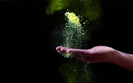 Hand holding yellow holi powder for color festival on black background, panorama, copy spaceの写真素材