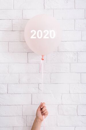 Promotion banner. Pink balloon with 2020 numbers in woman hand on white backgroundの写真素材