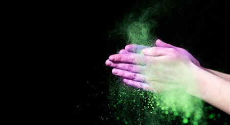 Happy holi. Colorful powder in clapping hands on black background, panorama, copy spaceの写真素材