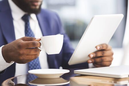 African American Business Guy Having Coffee And Working On Tablet At Outdoor Cafe. Closeup, Selective Focusの写真素材