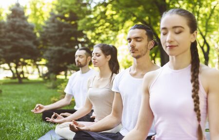 Group Of Young People Meditating at Yoga Class Outdoors, Close Upの写真素材