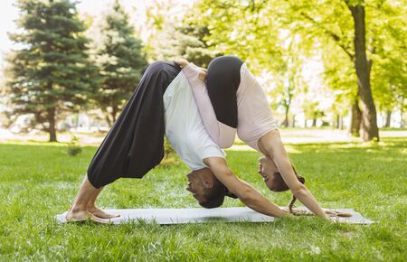 Young And Healthy Couple Practicing Yoga Together Showing Strength And Flexibility, side view and copy spaceの写真素材