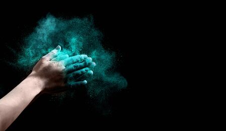 Green holi powder explosing from woman hands on black background, panorama, free spaceの写真素材