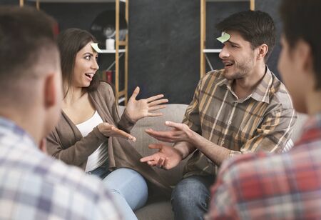 Engrossed couple enjoying playing forehead detective game, guys turn to guessの写真素材