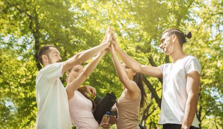 Teamwork and unity concept. Closeup Of Young Yoga Lovers Giving High Five After Successful Training...