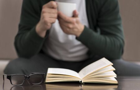 Caucasian Businessman Reading Book At Home, studying business literature and enjoying coffee,...