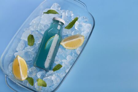 Blue detox water for refreshing in the summer on ice with lemon slices and mint leaves, background