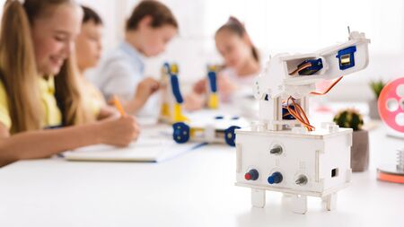 Children studying in class with robot at foreground, copy space