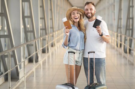 Traveling concept. Loving couple holding passports with tickets, waiting for departureの写真素材