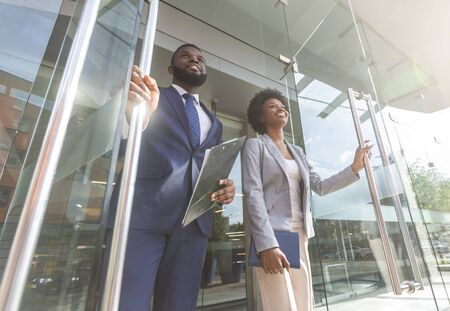Happy confident african american business people walking out of modern office center after successful meeting. Low-Angle Shot with copy spaceの写真素材