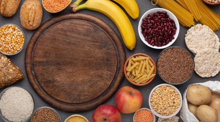 Gluten free food with grains and fruits around copy space on cutting board, wooden background, panoramaの写真素材