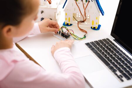 Stem lesson. Schoolgirl programming robot with laptop computer, building electric toy