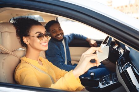 Road trip. Happy couple taking selfie in car, driving to new destination