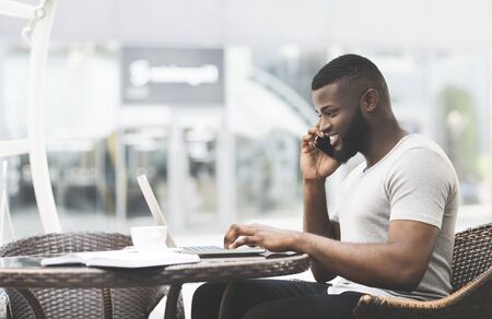 African guy talking with friend and planning the date of party on his laptop, panorama, copy space