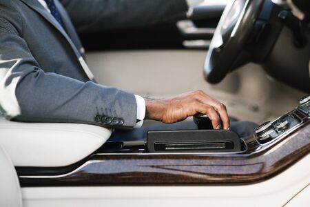 Businessman driving car, holding hand on gearbox, going to work, side view