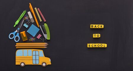 Back to school concept. Yellow american bus with stationery on the top on chalk board background, panoramaの写真素材