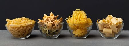 Italian menu concept. Different shape pasta with carbohydrates on black background, panoramaの写真素材