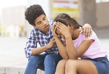 Young african american guy comforting his sad girlfriend that crying on public, copy space
