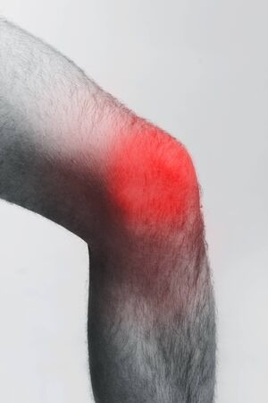 Trauma, stretching. Monochrome photo of male leg with red zone of injured knee, closeupの写真素材