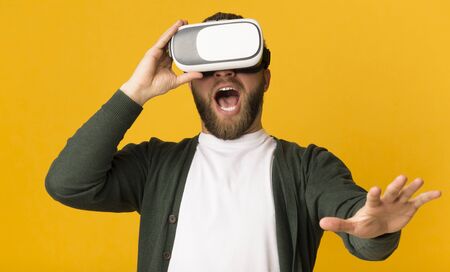 Stunning experience with new technologies. Middle aged man having good time with vr glasses on, raising his hand, panoramaの写真素材