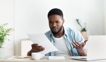 Frustrated african american employee shocked by reading financial report of his company filled with mistakes and inaccuracies. Panorama with copy spaceの写真素材