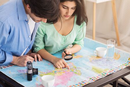 Couple searching best route on map, planning trip and preparing for vacation