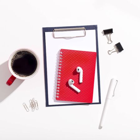 Red Cup of coffee, earphones and notebook on white office tableの写真素材