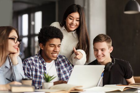 College students using laptop in library, studying together for school assignmentの写真素材
