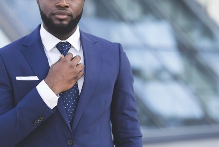 Business Life. Unrecognizable Afro Businessman Adjusting Necktie Walking In City Center, Cropped, Empty Spaceの写真素材