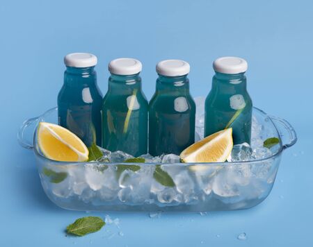 Creative set of blue detox cocktail with fresh lemons and ice cubes on backgroundの写真素材