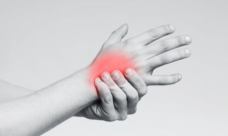 Young man with pain in hand, rubbing his inflamed back of hand, monochrome panorama photo