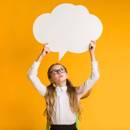 Thinking Of School. Pensive Little Schoolgirl Holding Speech Bubble Overhead On Yellow Background....