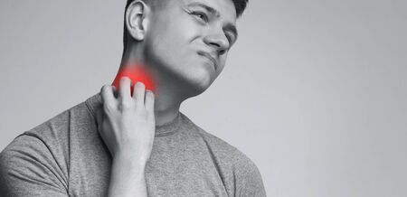 Thyroid problem. Young man scratching his neck, painful rash, panorama with empty space