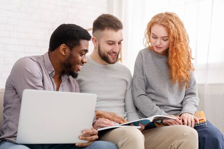 Friends preparing for exams together, using laptop and reading books at home